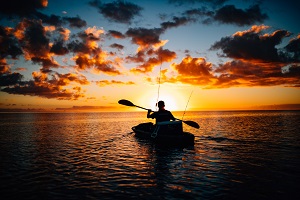 黄昏时分，男子划着钓鱼皮艇188bet亚洲体育真人投注
