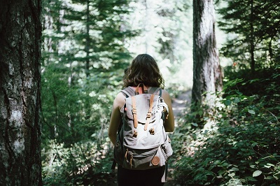 女孩背着背包在树林里徒步旅行