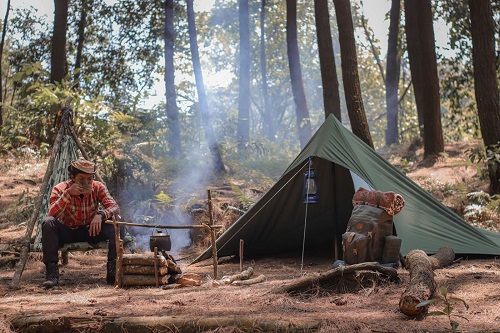 一个人坐在营火和帐篷旁边