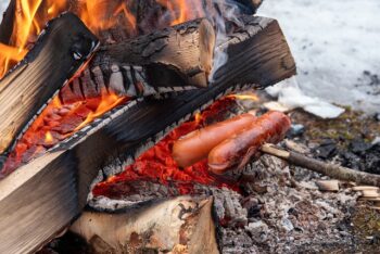 hotdogs cooking over campfire